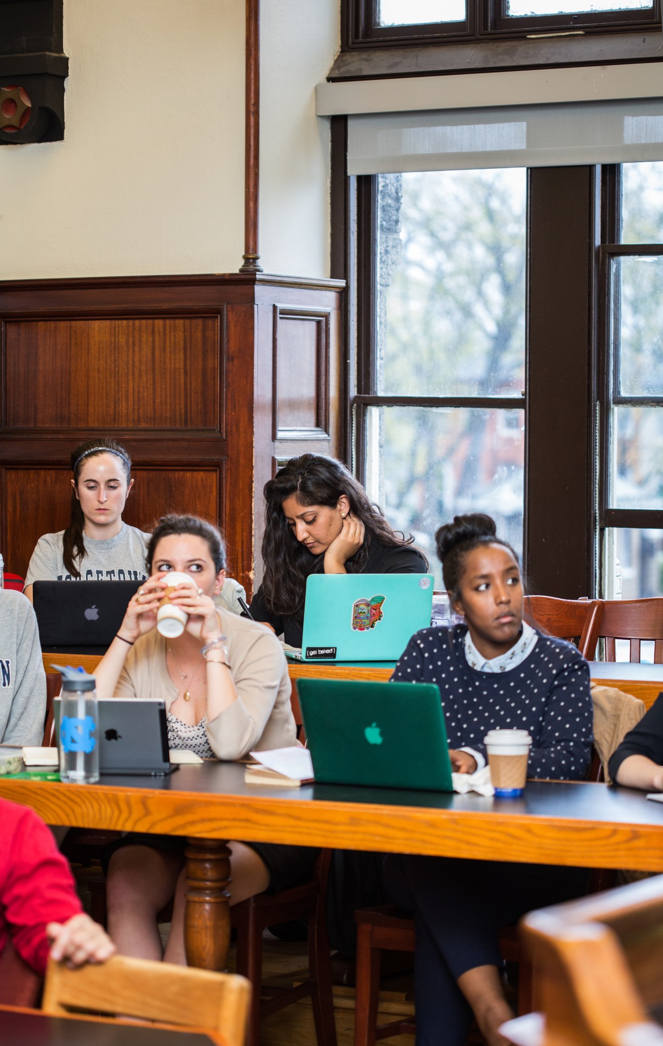 Students study with laptops in a wood-paneled classroom at Georgetown University's Healy Hall.