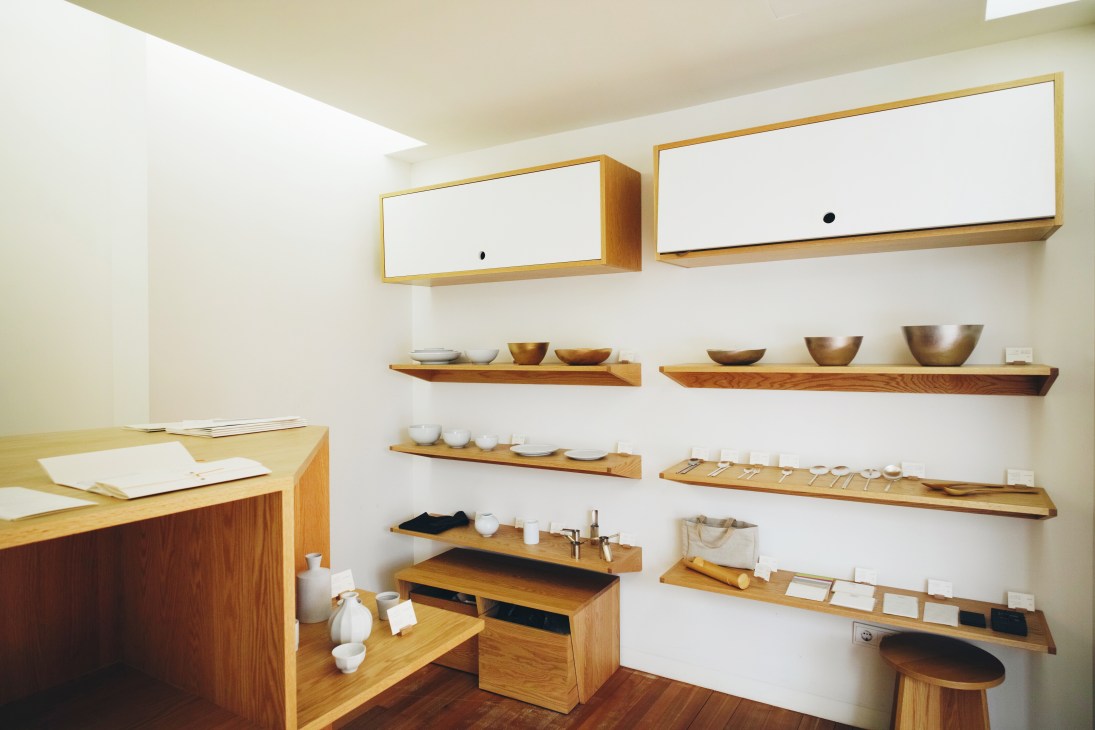 Arumjigi Foundation shop displaying Korean ceramics, bowls and spoons on wooden shelves against white walls.