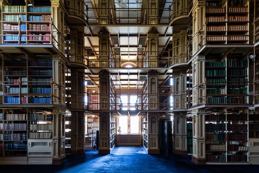 Interior of Riggs Library with ornate wooden shelving, gold-leaf details, and natural light from skylight.