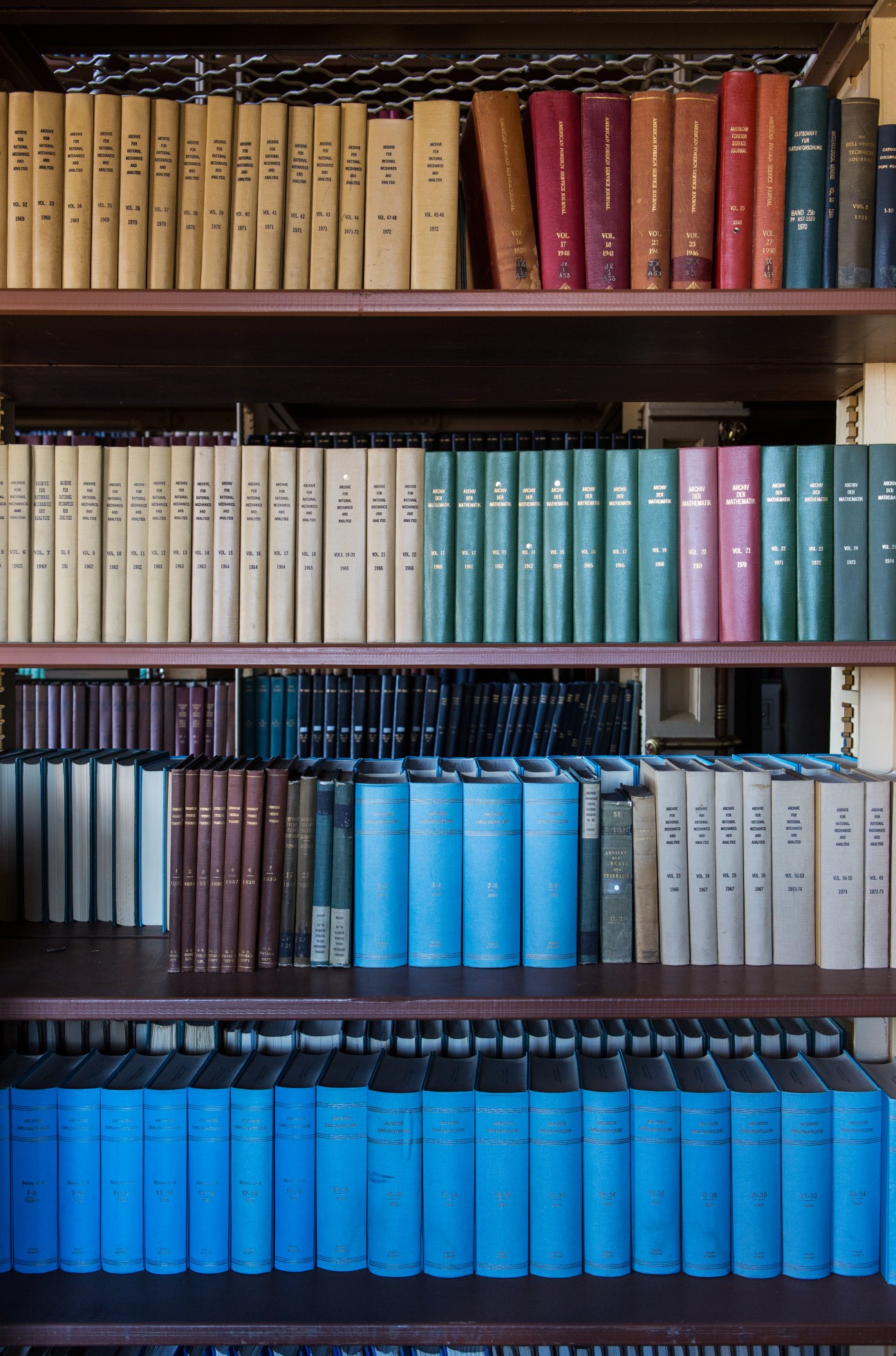 Shelves of antique books in various colors arranged in Riggs Library.