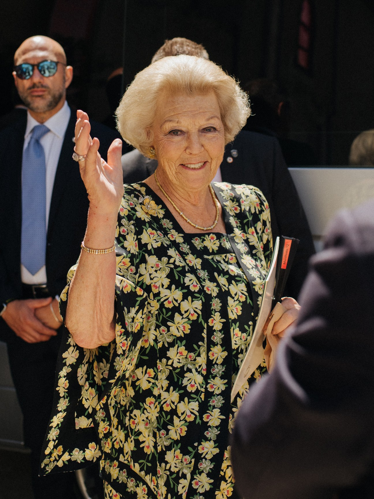 Princess Beatrix, former Queen of the Netherlands, waving at Manifesta in Palermo wearing a floral dress.