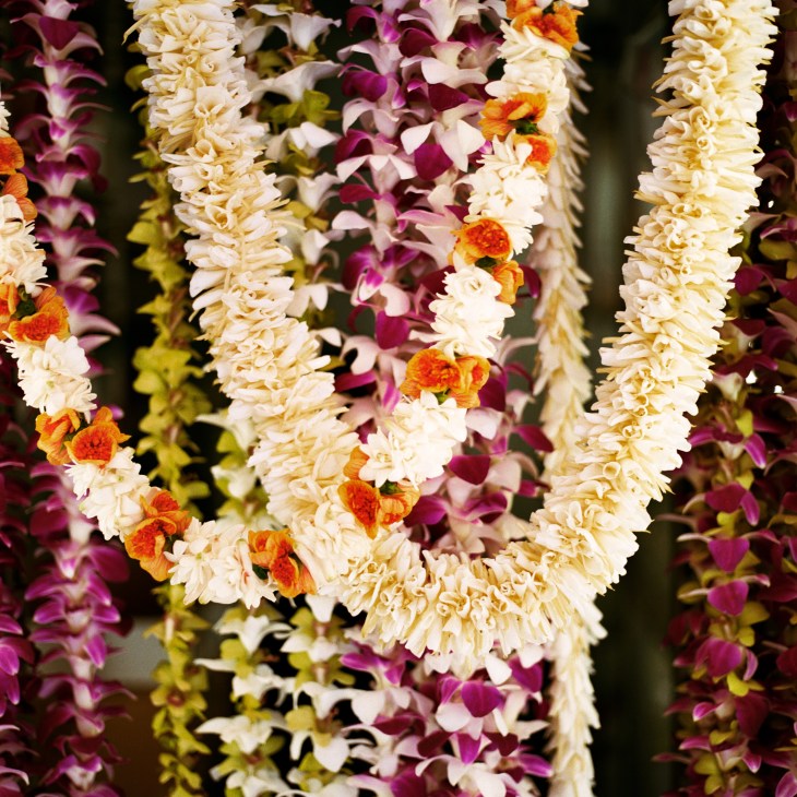 Colorful lei garlands with white, pink, purple and orange flowers strung together.
