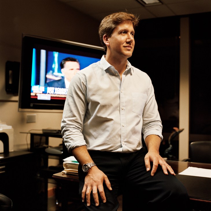Craig Carapelho of Team Vision stands in an office with a television screen in the background.