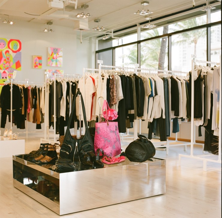 Interior of Aloha Rags Honolulu shop displaying clothing on racks and accessories on central display table.