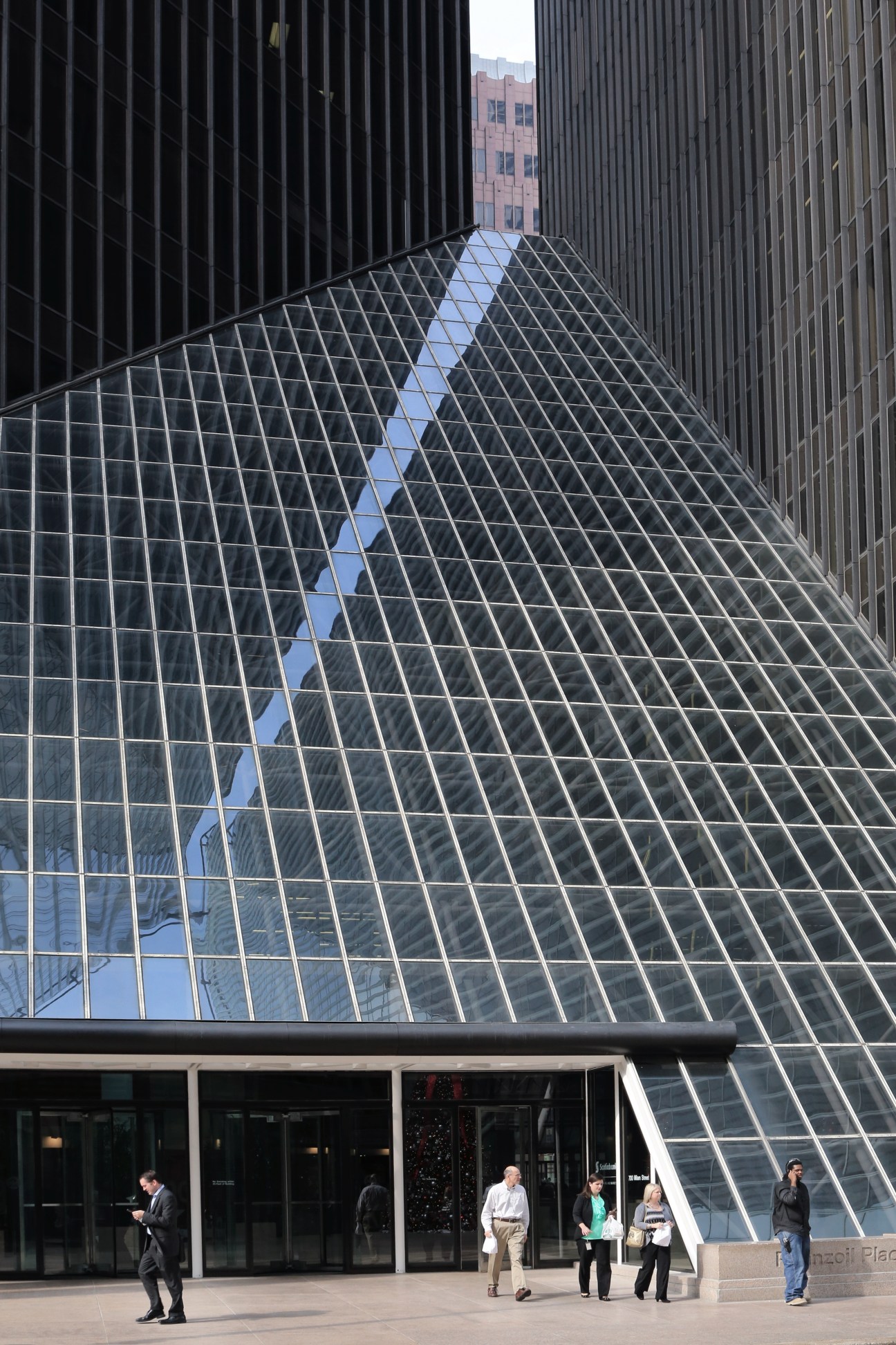 Pennzoil Place's distinctive diamond-patterned glass and steel facade with pedestrians on the plaza below.