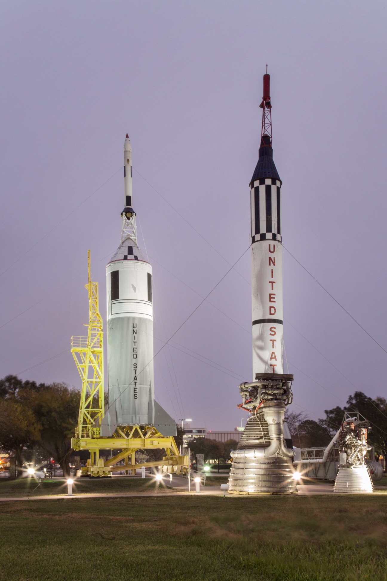 Two rocket spacecraft displayed at NASA's Johnson Space Center in Houston at dusk, including a United States rocket.