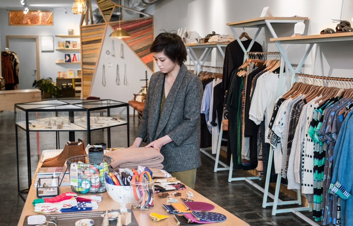 Trang Nguyen arranges textiles at Myth & Symbol, a craft and clothing shop in Houston.