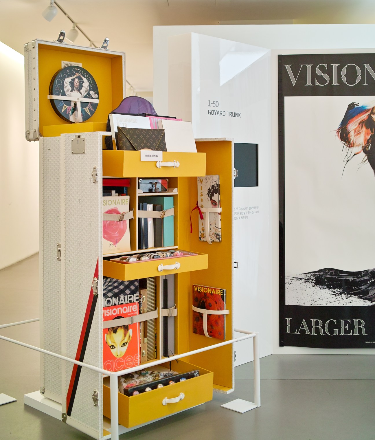 Yellow and white display cabinet with design artifacts and publications in Hyundai Card Design Library exhibition space.