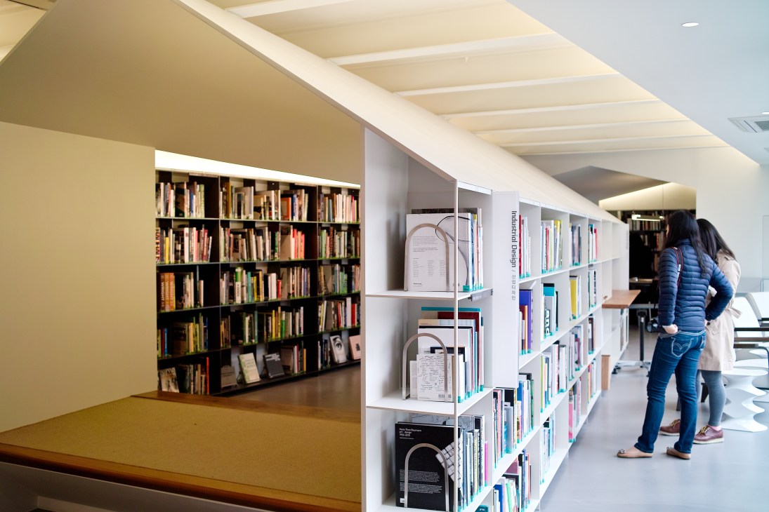 Visitors browse shelves of design books in the minimalist interior of the Hyundai Card Design Library.