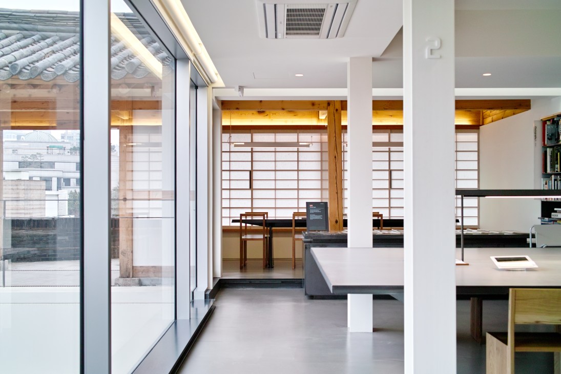 Interior of Hyundai Card Design Library reading room with minimalist design, wooden screens, and clean white surfaces.