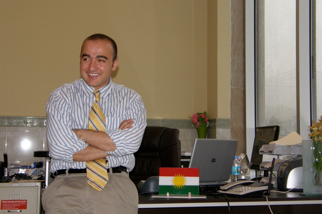 Ibrahim Abdullatif, a 31-year-old businessman, standing in his office with arms crossed, wearing a striped shirt and tie.