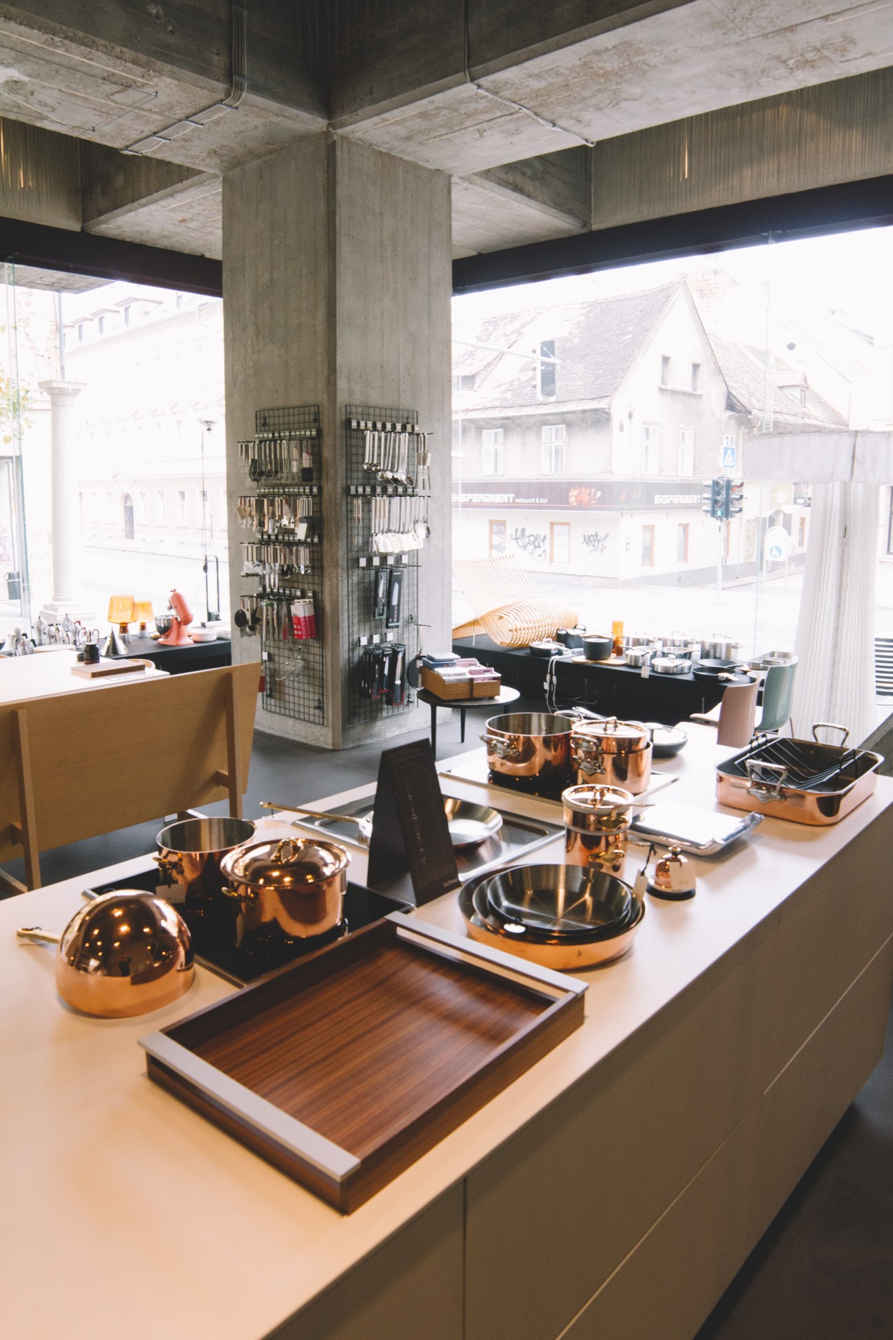Interior of ID: Doma design shop displaying copper cookware and kitchen utensils on white counter.