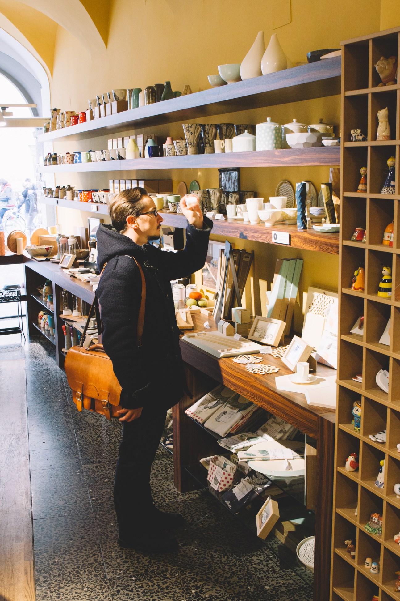 Person browsing shelves of homewares and products at Ika design shop in Ljubljana
