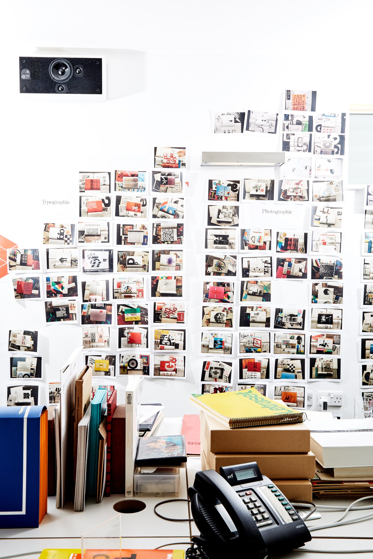 Unit Editions studio wall with hundreds of printed design publications and reference materials pinned in organized rows.