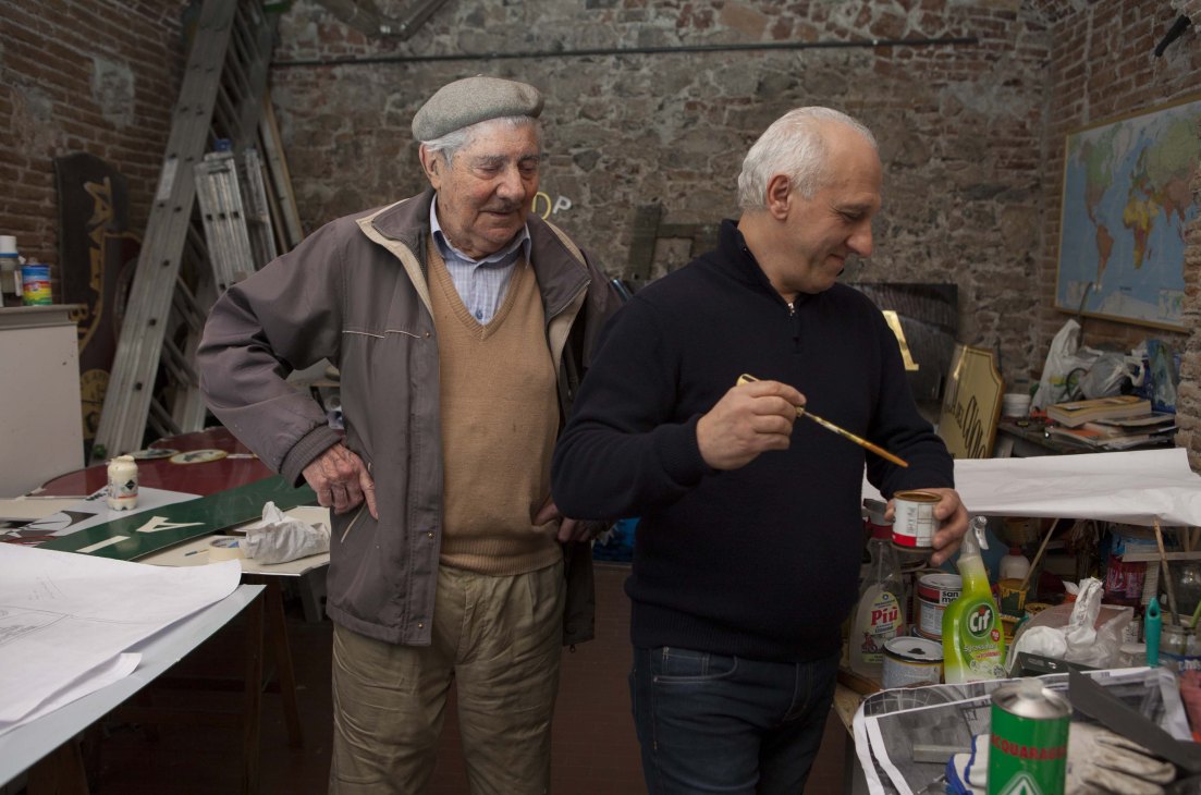 Signmakers Alberto Berra and Germano Romeo in their workshop with brushes and materials.