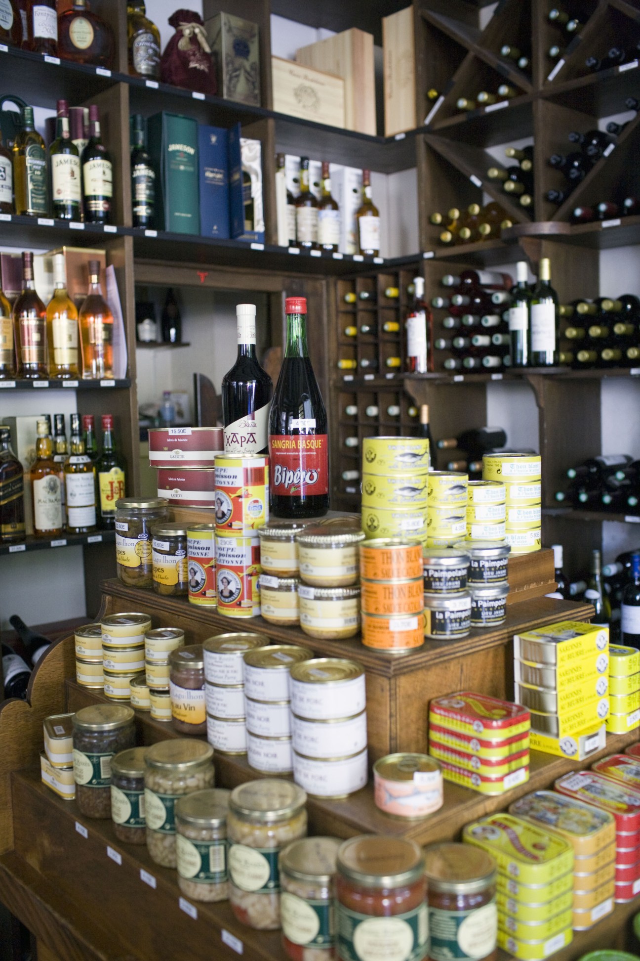 Interior of Caves Bordelaises wine shop displaying bottles and gourmet products on wooden shelves and counter.