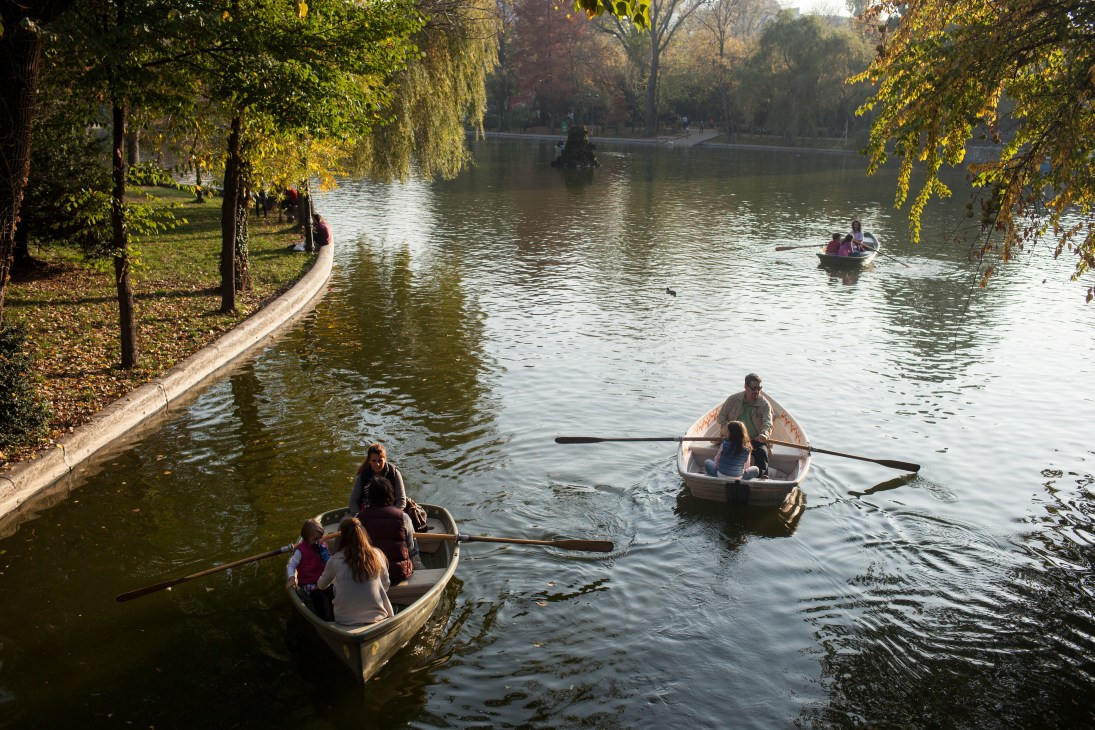 People rowing boats on a lake surrounded by autumn trees at Cismigiu Gardens in Bucharest.