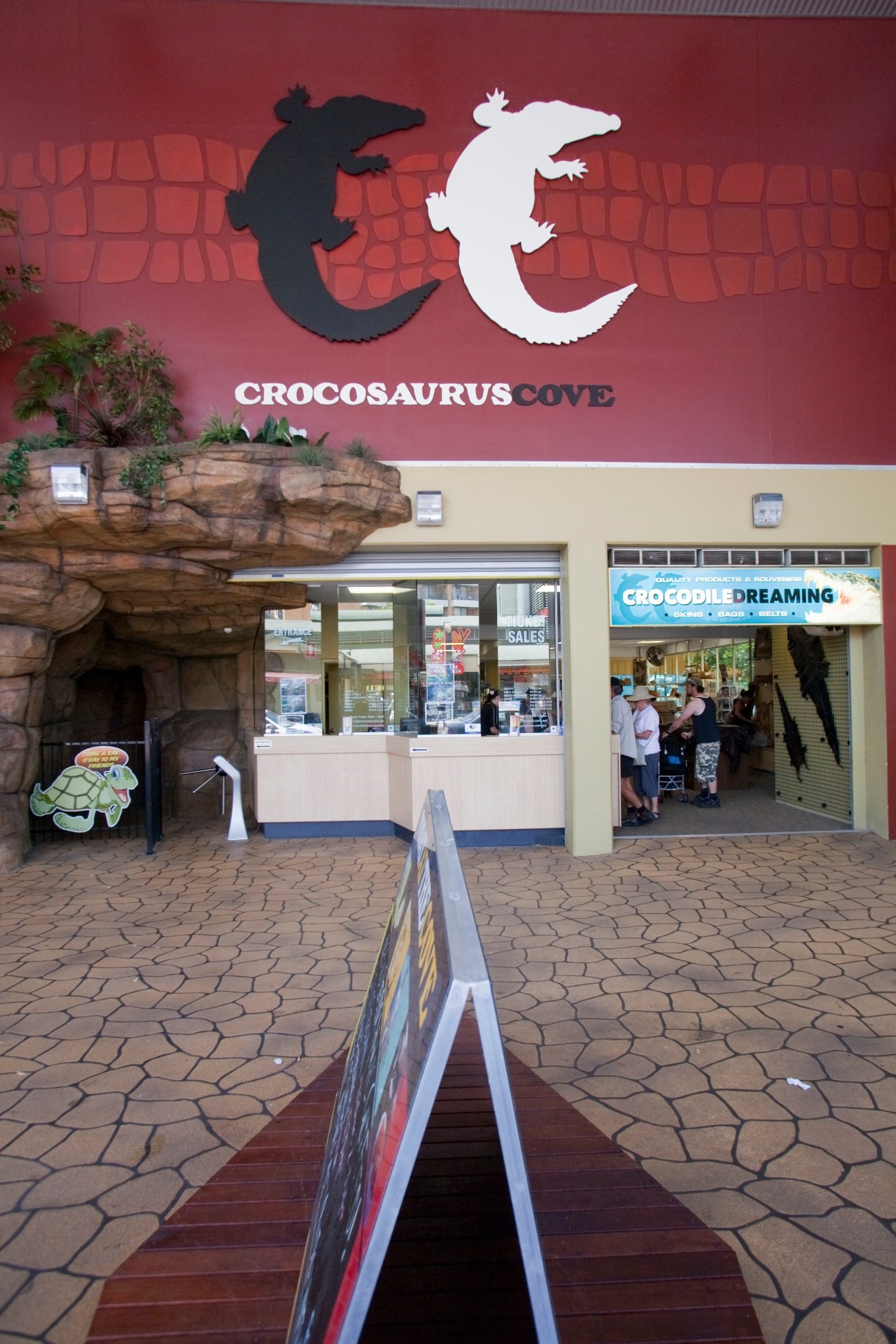 Entrance to Crocosaurus Cove tourist attraction with red facade and crocodile logo signage in Darwin.
