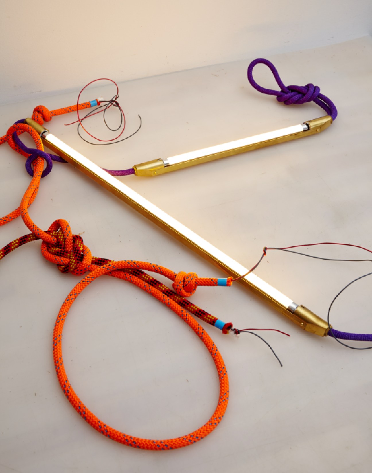 Bec Brittain's experimental lighting fixtures using colorful bungee cord with brass and LED components.