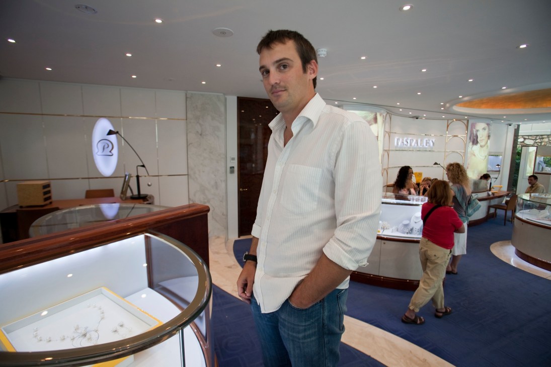 James Paspaley stands in a modern retail shop displaying pearl jewelry, with the Paspaley logo visible in the background.