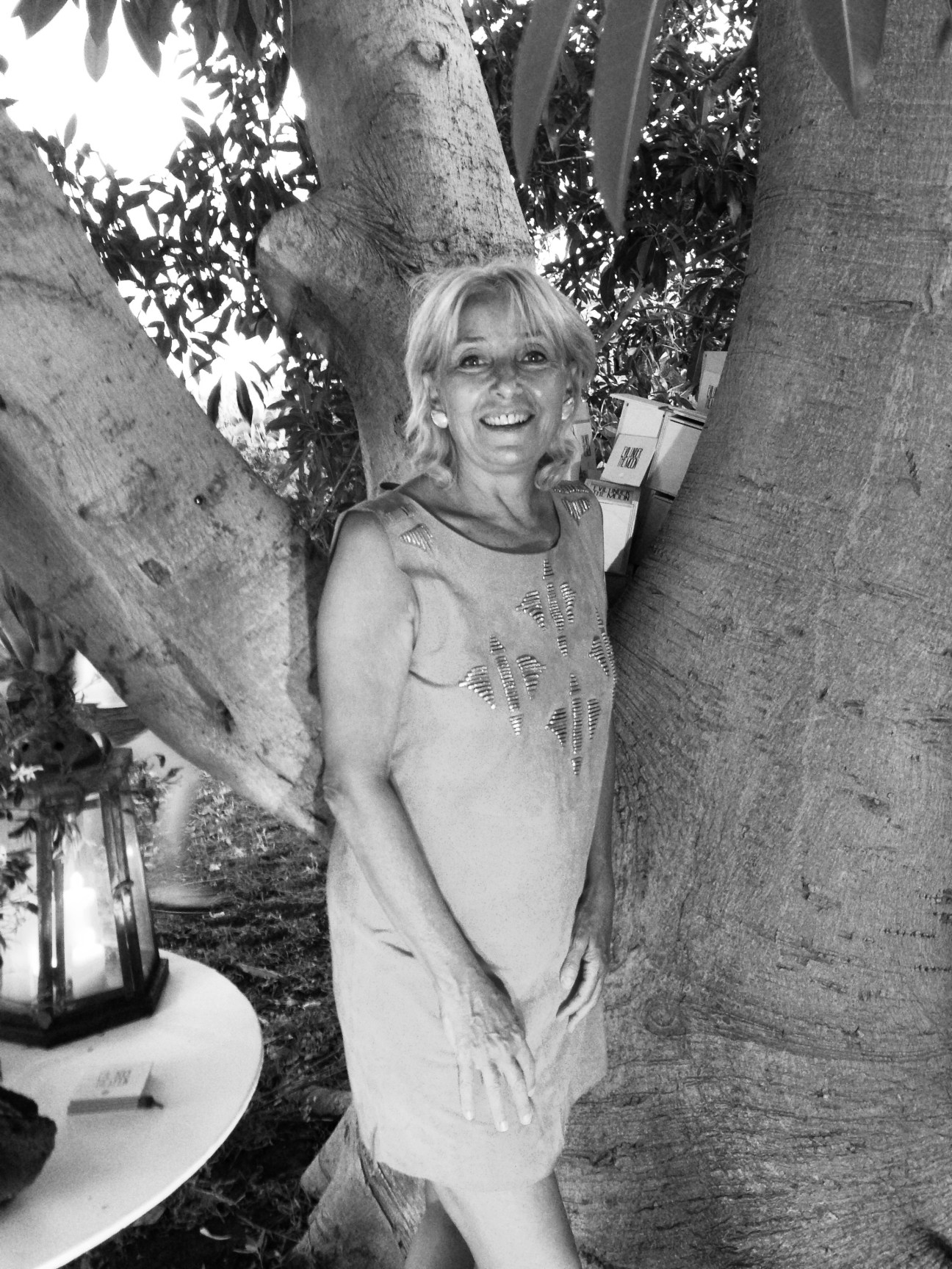 Black and white portrait of Nicoletta Fiorucci smiling between tree trunks outdoors.