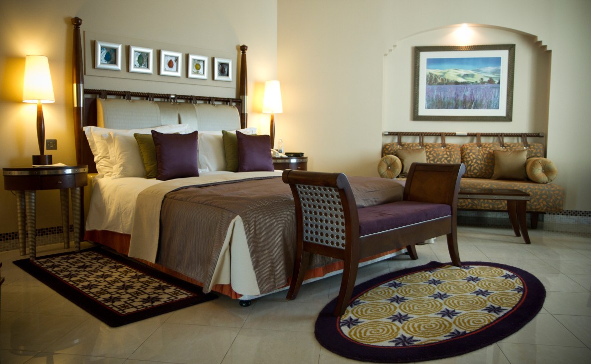 Luxurious hotel bedroom with elegant furnishings, decorative pillows, and framed artwork.