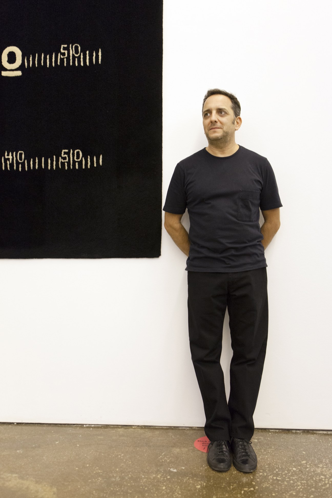 Architect Karim Bekdache standing in front of a black artwork with geometric markings