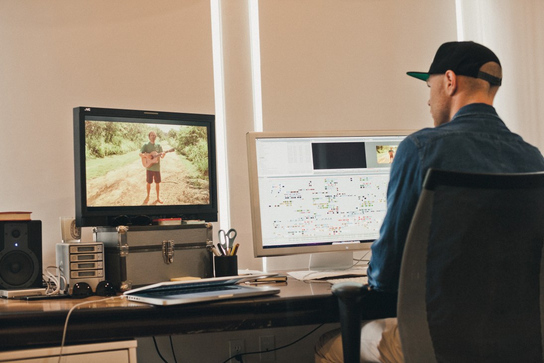 Garrett Darland editing video footage at Brushfire Records, with Jack Johnson footage displayed on monitor.