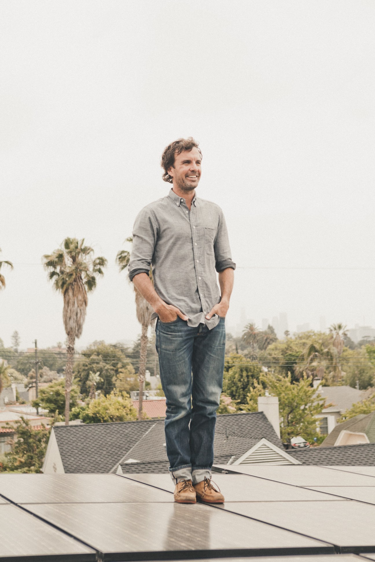 Brushfire Records co-owner Emmett Malloy stands on the roof among solar panels overlooking a residential Los Angeles neighborhood.