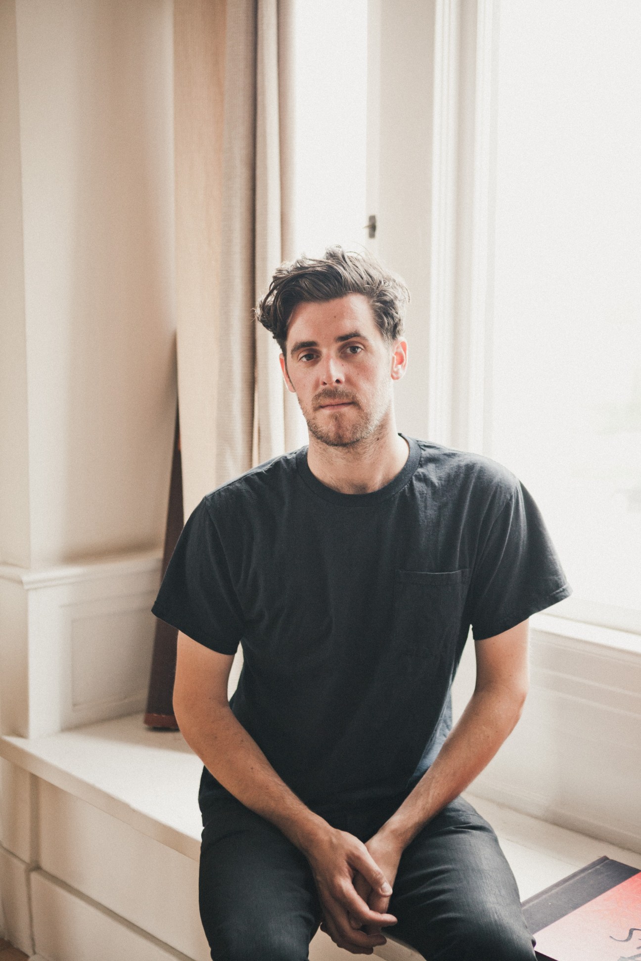 Daniel Pappas, Brushfire Records development director, sitting on a white ledge in a black t-shirt.