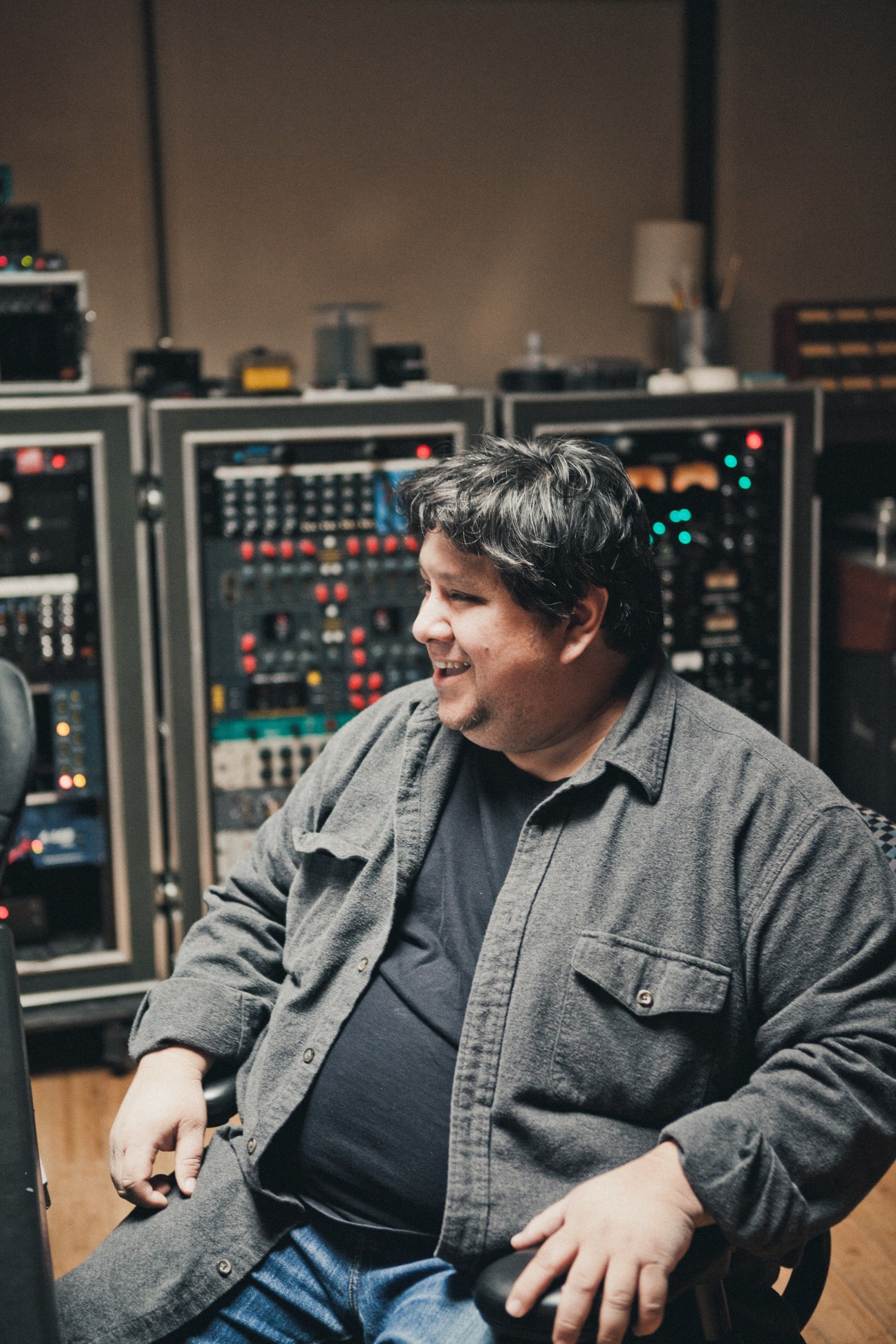 Robert Carranza, Brushfire's sound engineer, sits in front of vintage recording equipment in the studio.