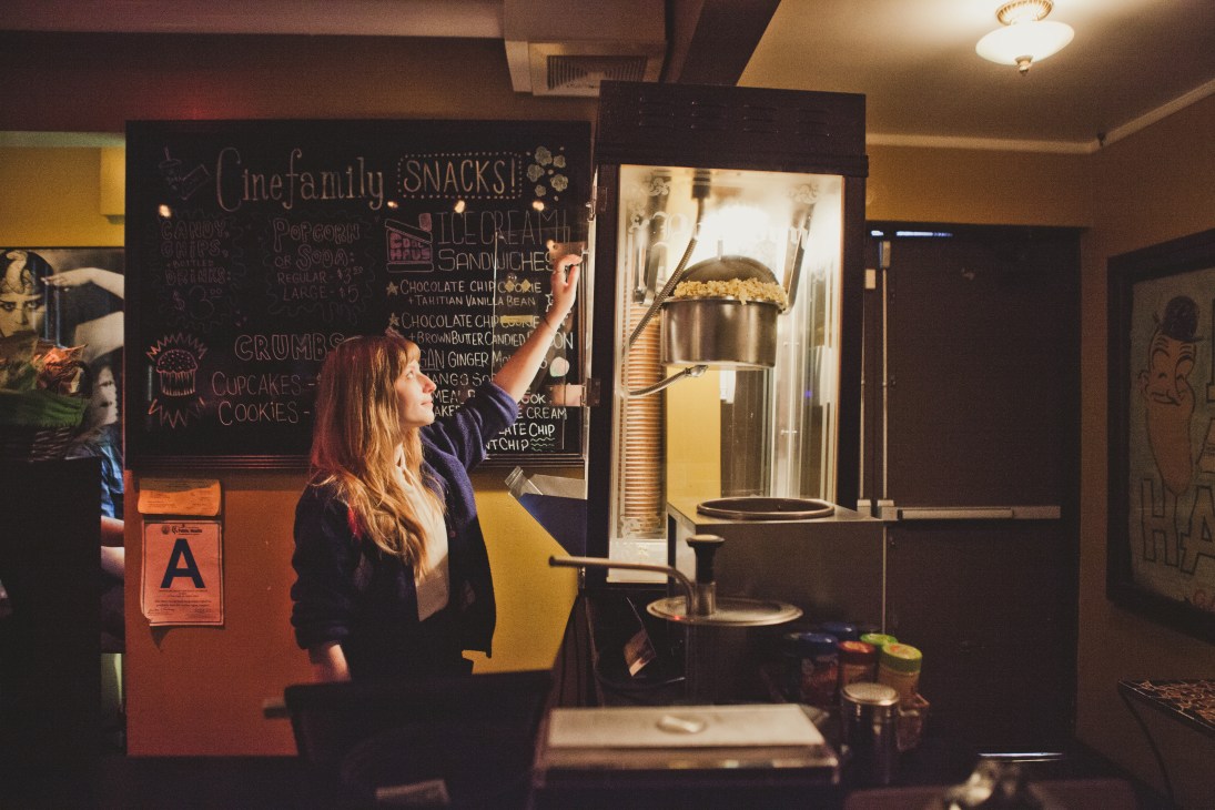 Cinefamily employee loading popcorn into a vintage machine at the Los Angeles cinema.