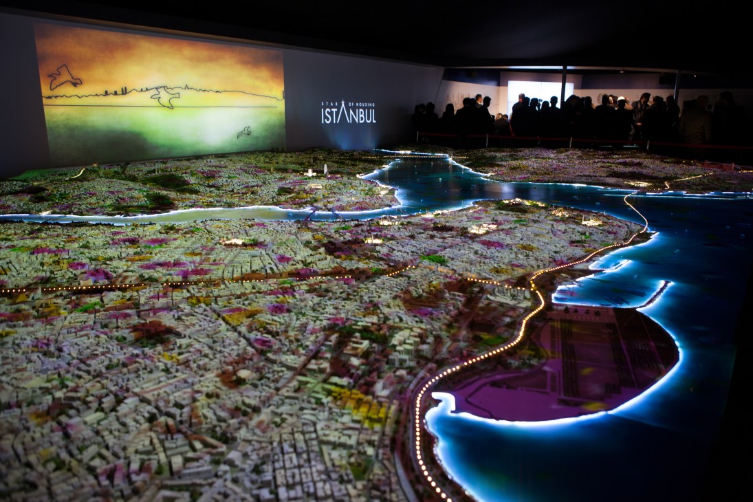 Illuminated architectural model of Istanbul with lit waterways and colored buildings displayed at Mipim property fair.