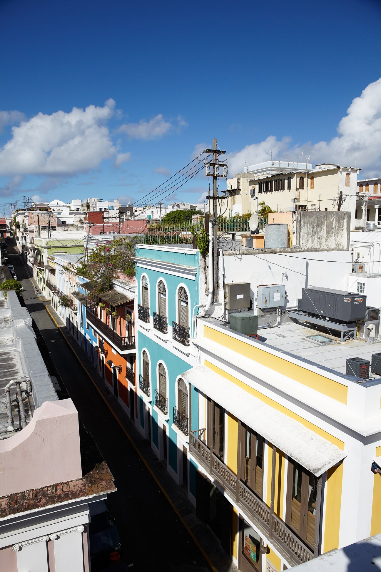 Colorful colonial buildings with turquoise and yellow facades line a narrow street in Old San Juan.
