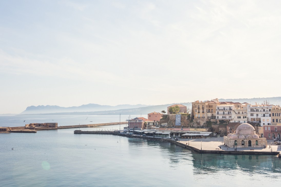 Chania harbor with historic Venetian architecture and mosque reflected in calm turquoise waters