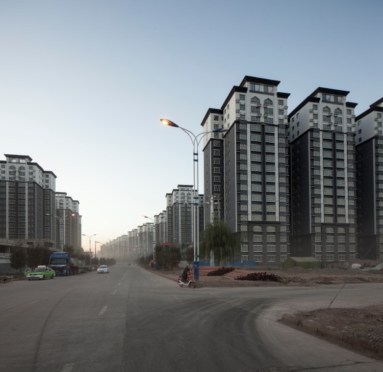 Wide street lined with identical multi-story residential tower blocks in new public housing development, Kashgar.