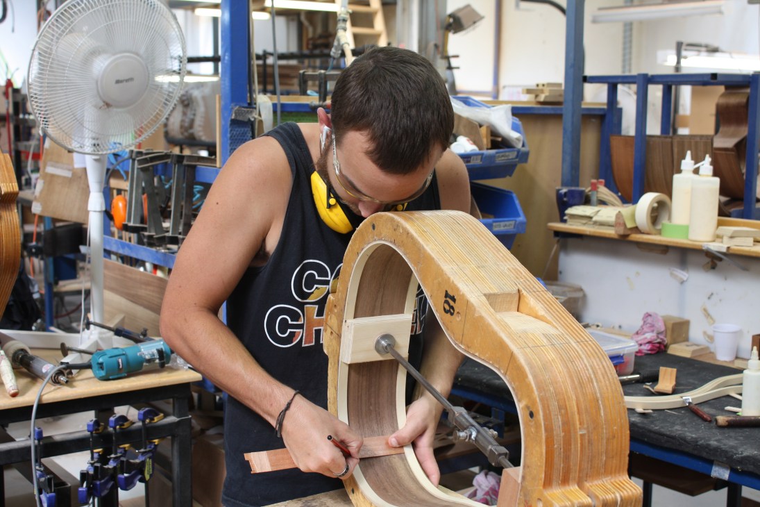 A craftsperson works on the wooden body of an acoustic guitar at Maton's Melbourne factory.