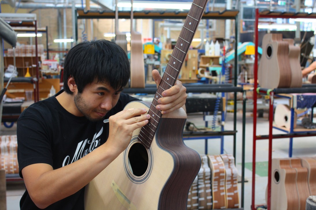 Worker performing fretwork on a Maton acoustic guitar in the Melbourne factory.