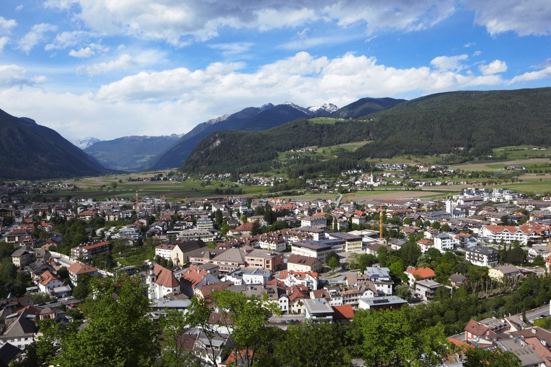 Panoramic view of the Puster Valley in South Tyrol with villages nestled among forested mountains and snow-capped peaks.