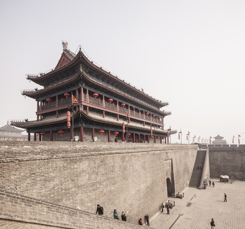 Traditional Chinese pagoda with upturned eaves and red lanterns on Xi'an's ancient fortified city wall.