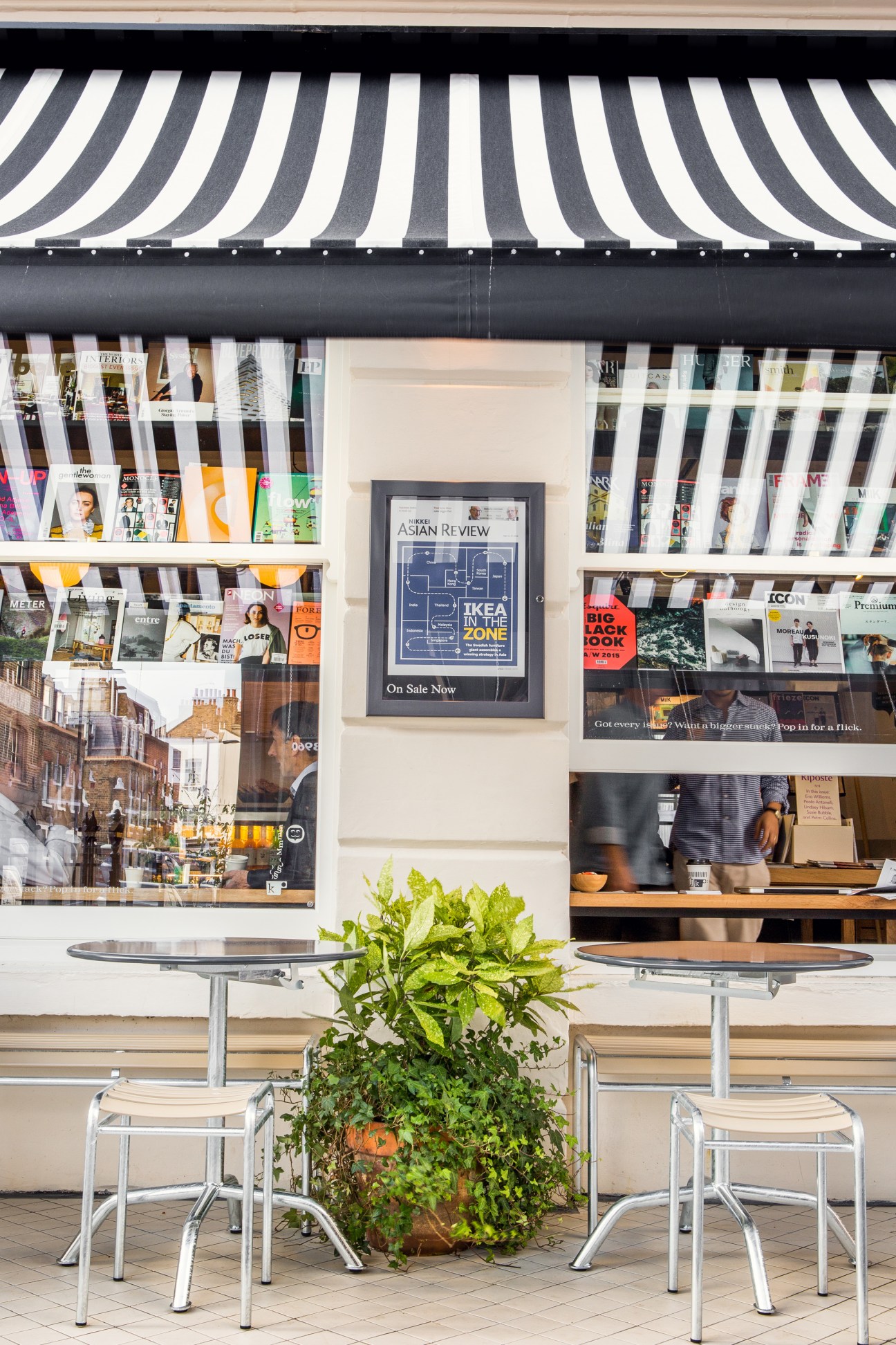 Striped awning and storefront of Kioskafé newsstand near Paddington Station, London.