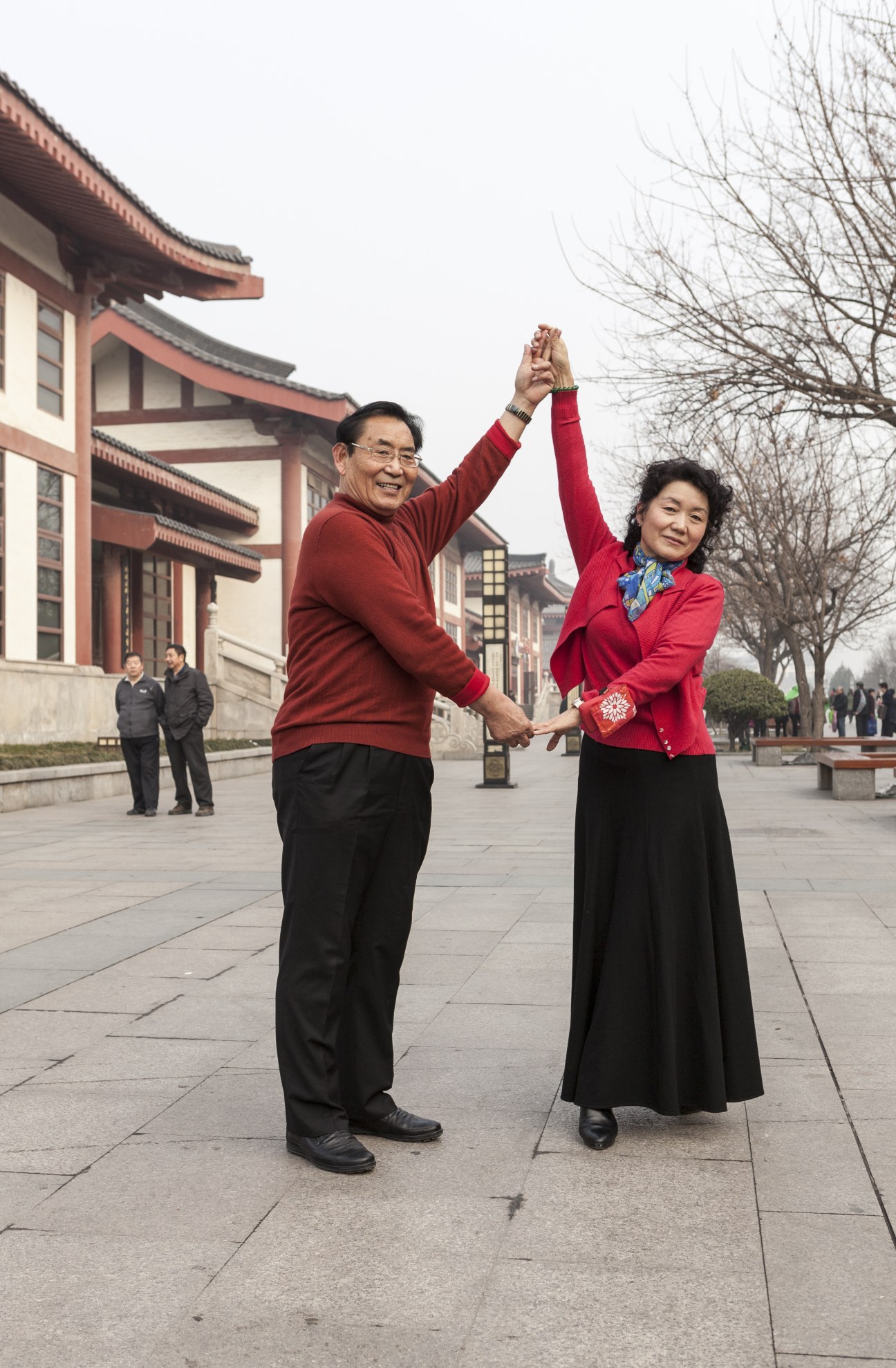 Two people in red clothing raise their joined hands in celebration at Giant Wild Goose Pagoda Square in Xi'an.