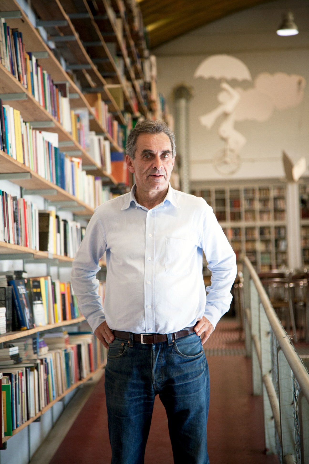 José Pinho, owner of Ler Devagar bookshop in Lisbon, standing among curved wooden bookshelves filled with colorful books.