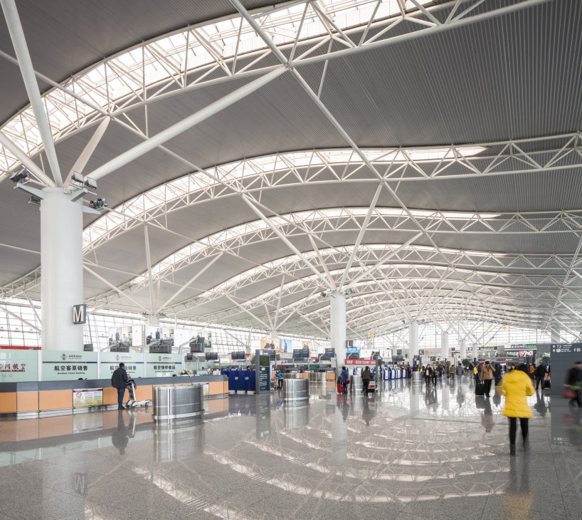 Interior of Xi'an Xianyang International Airport Terminal 3 with white steel lattice ceiling structure and polished floor.