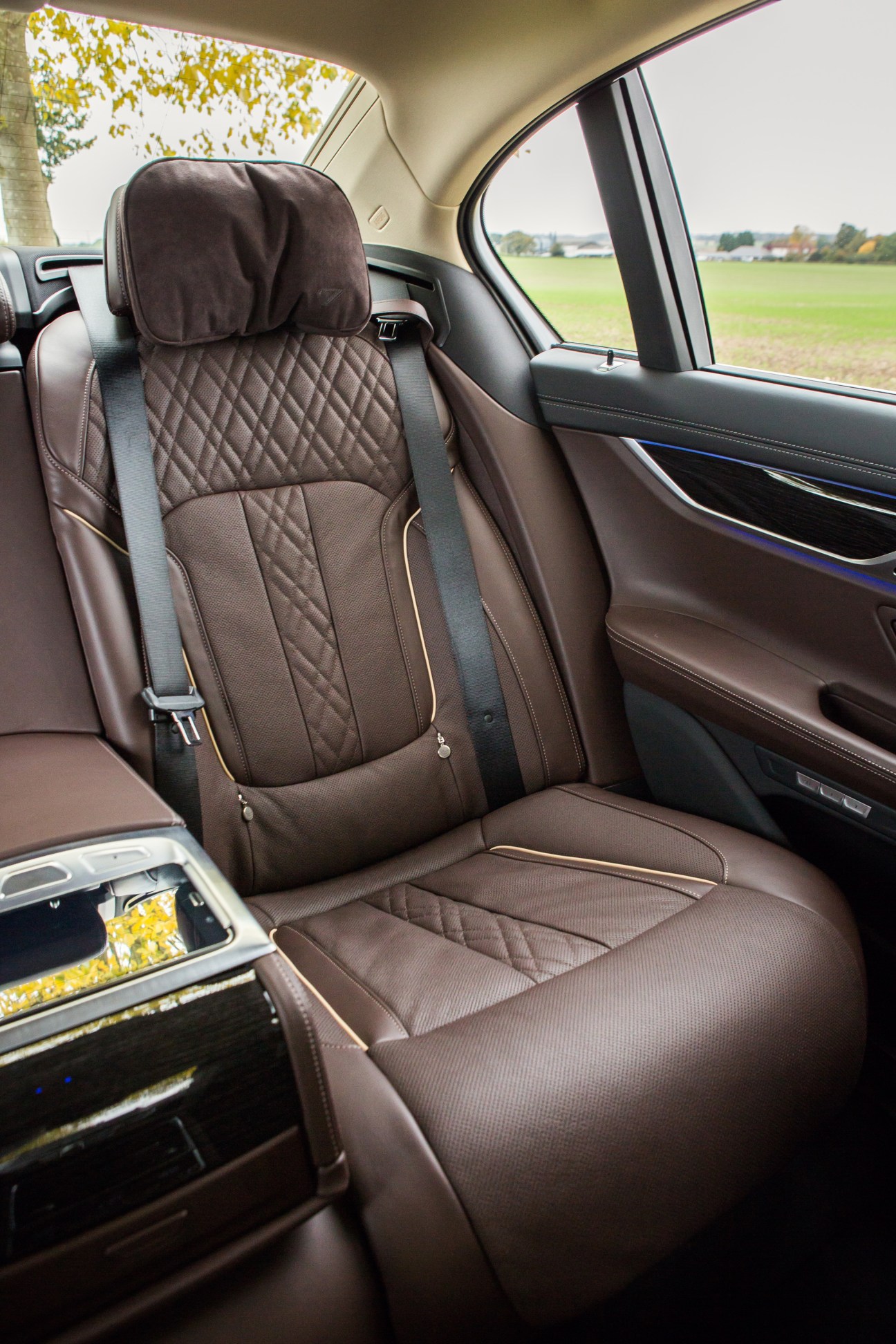 Brown leather rear seat interior of BMW 7 Series with quilted headrest and adjustable features.