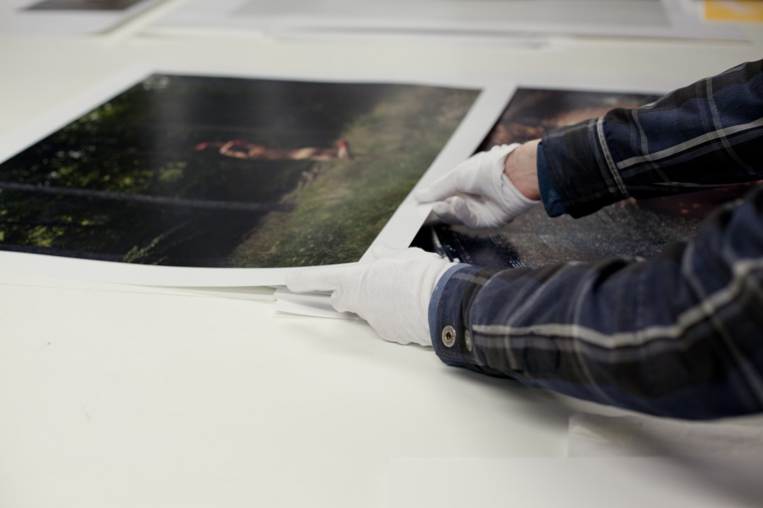 Person wearing white gloves examining a framed photograph at Photo Art Fair, London.