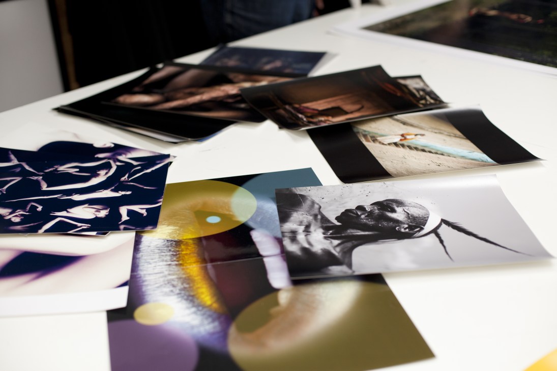Photographs and prints spread across a white table at Photo Art Fair, London.