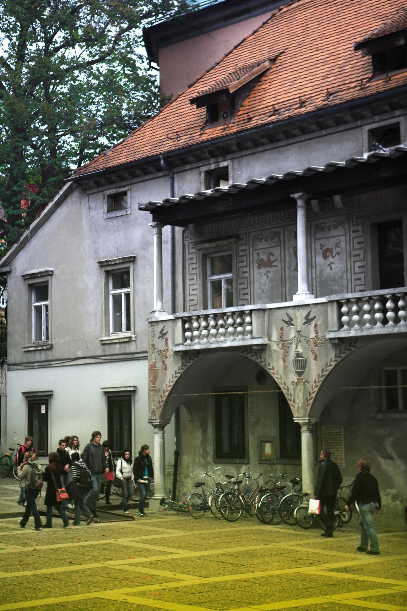 The Križanke, an 18th-century monastery with terracotta roof, ornate arches and decorative columns, now functions as a cultural centre with visitors and bicycles in the courtyard.