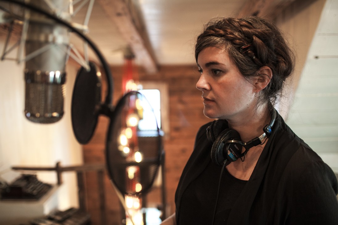 Musician Julianna Barwick recording at a microphone in a studio.