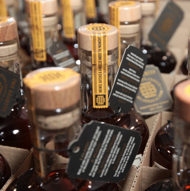 Bottles of Yukon Brewing single-malt whisky with wooden corks and gold foil wrapping displayed in packaging.